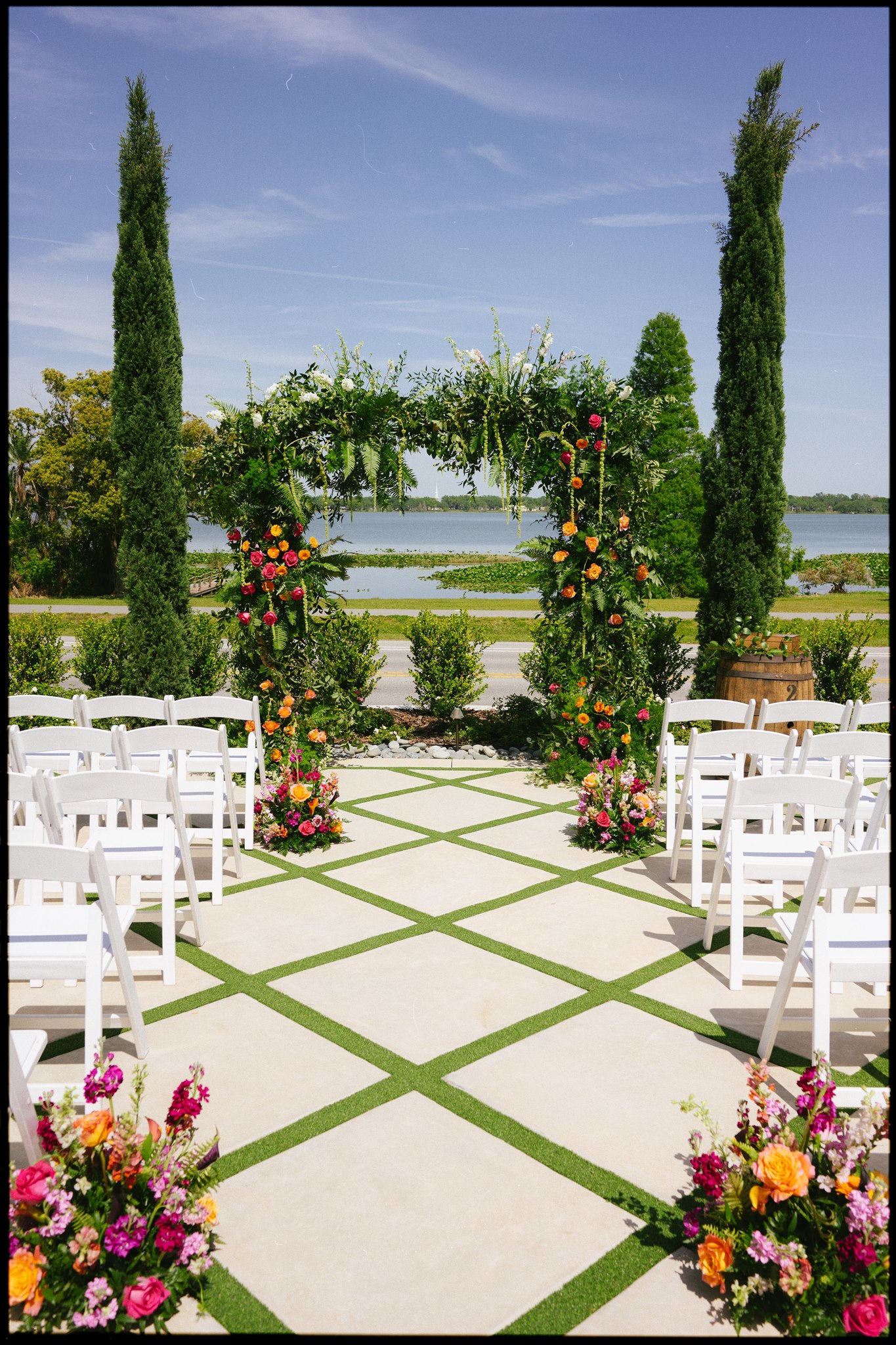 Large wedding floral arch with lush aisle flowers in a vibrant, colorful palette