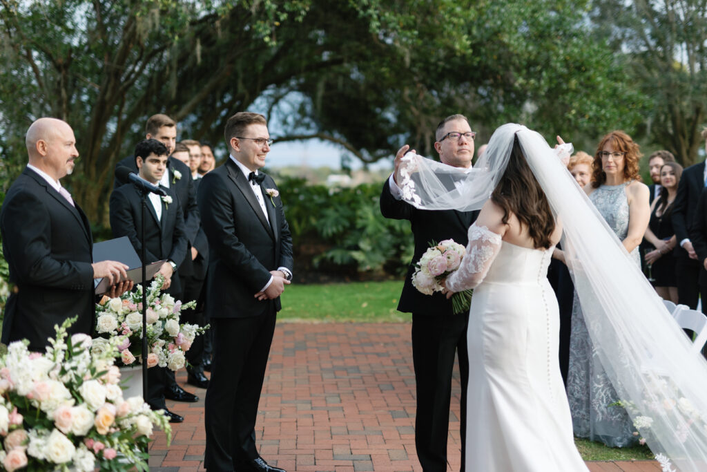 Father removing bride’s veil after walking her down the aisle at Adams Estate